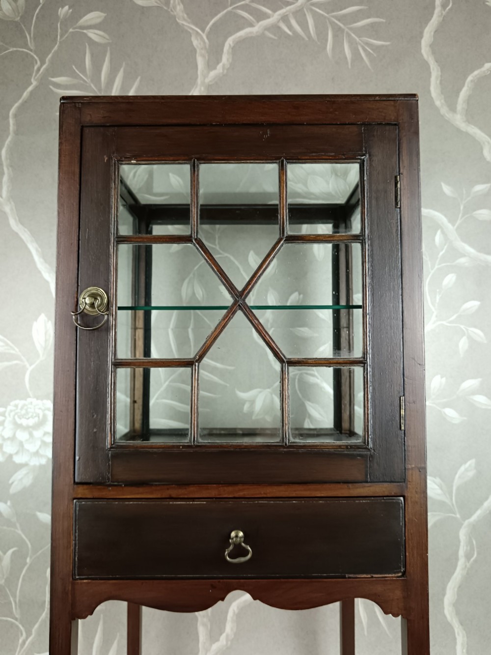 A Georgian mahogany vitrine cabinet featuring glazed side panels, a single lower drawer, straight tapered legs, and a glazed front door with geometric astragal glazing bars. View VI