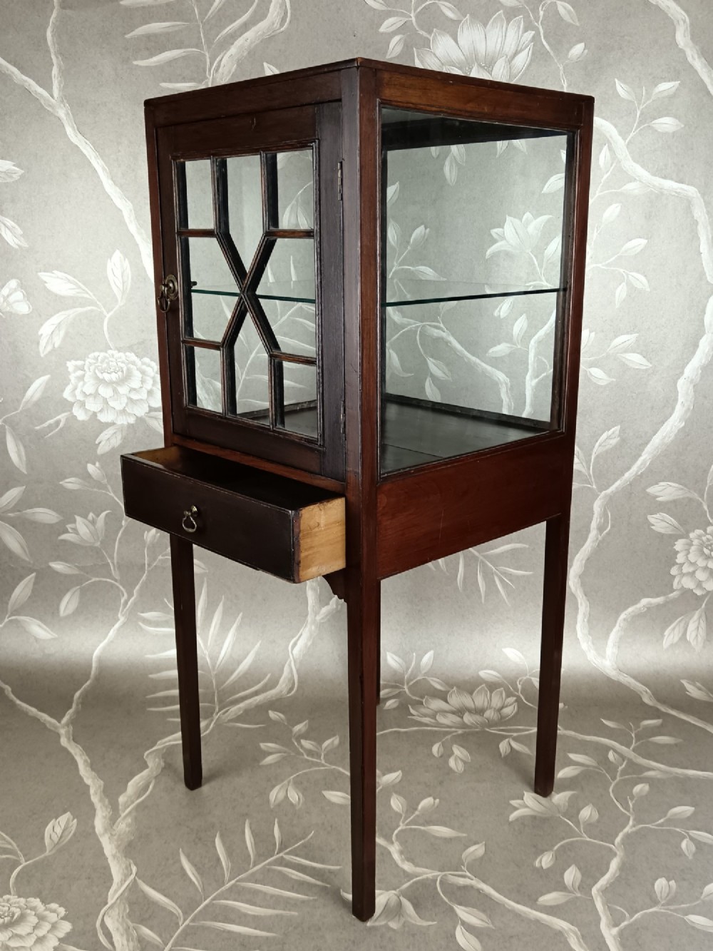 A Georgian mahogany vitrine cabinet featuring glazed side panels, a single lower drawer, straight tapered legs, and a glazed front door with geometric astragal glazing bars. View X