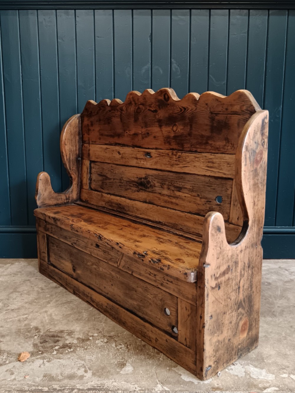 An antique 19th-century country pine and elm settle bench with a high scalloped cresting rail and a warm brown waxed timber finish. View II