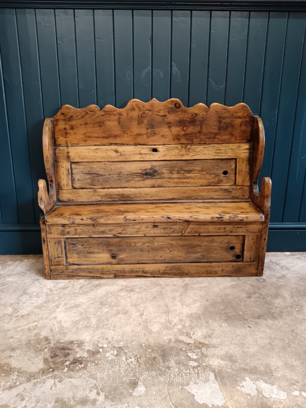 An antique 19th-century country pine and elm settle bench with a high scalloped cresting rail and a warm brown waxed timber finish. View V
