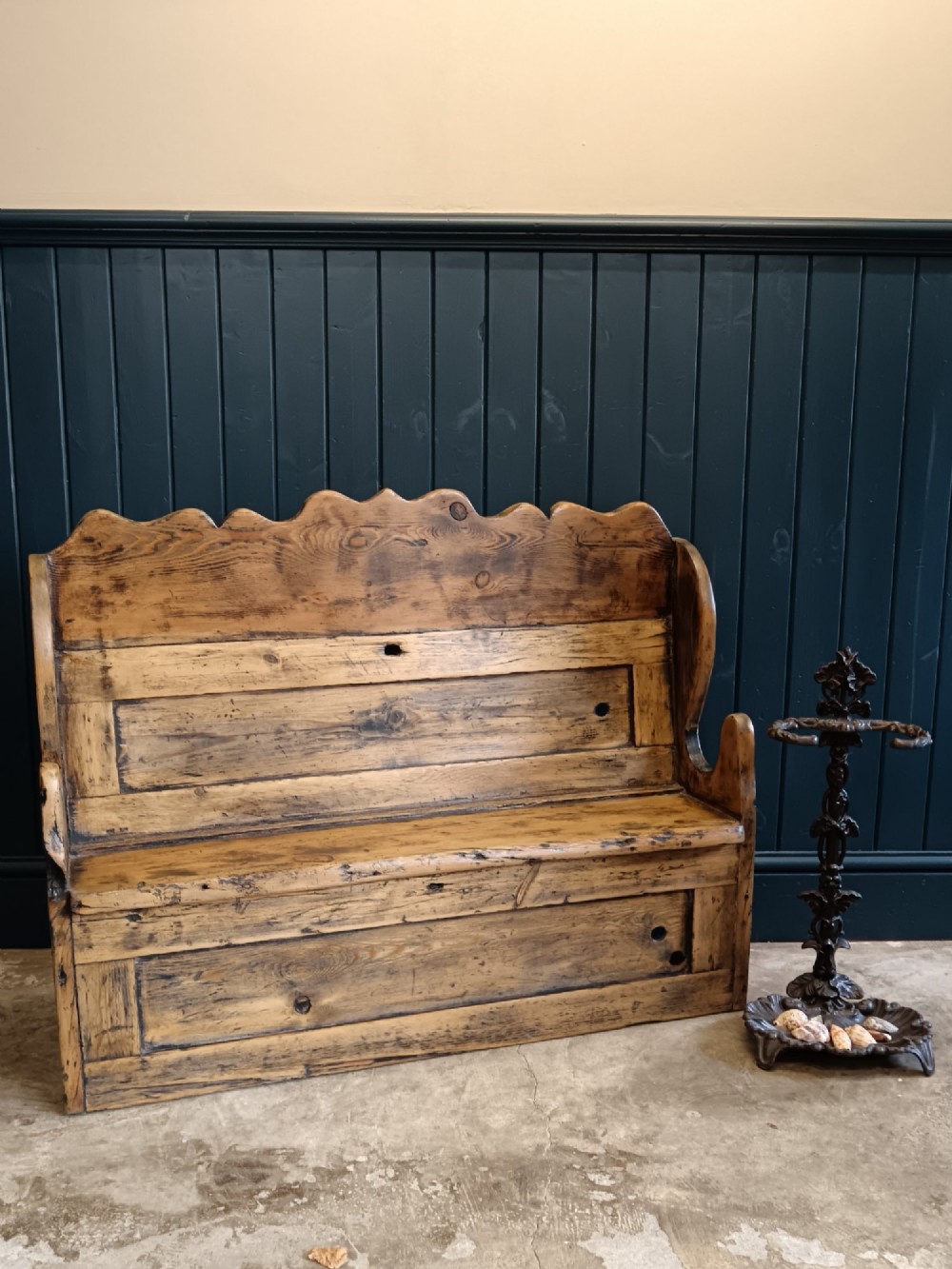 An antique 19th-century country pine and elm settle bench with a high scalloped cresting rail and a warm brown waxed timber finish. View VI