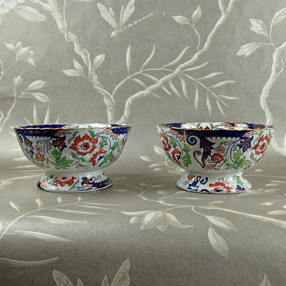 A pair of 19th-century Minton ironstone pedestal bowls with scalloped rims and vibrant Amherst Japan floral transfer pattern in cobalt blue, orange, and green.