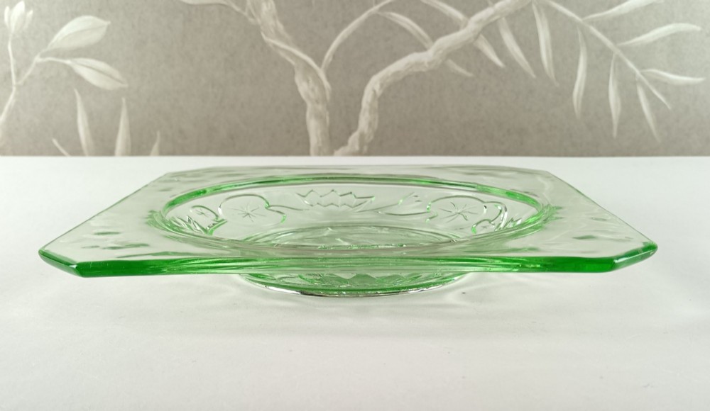 A square pale green Art Deco pressed glass plate featuring a central circular design of two swimming fish surrounded by embossed water lilies. View IV