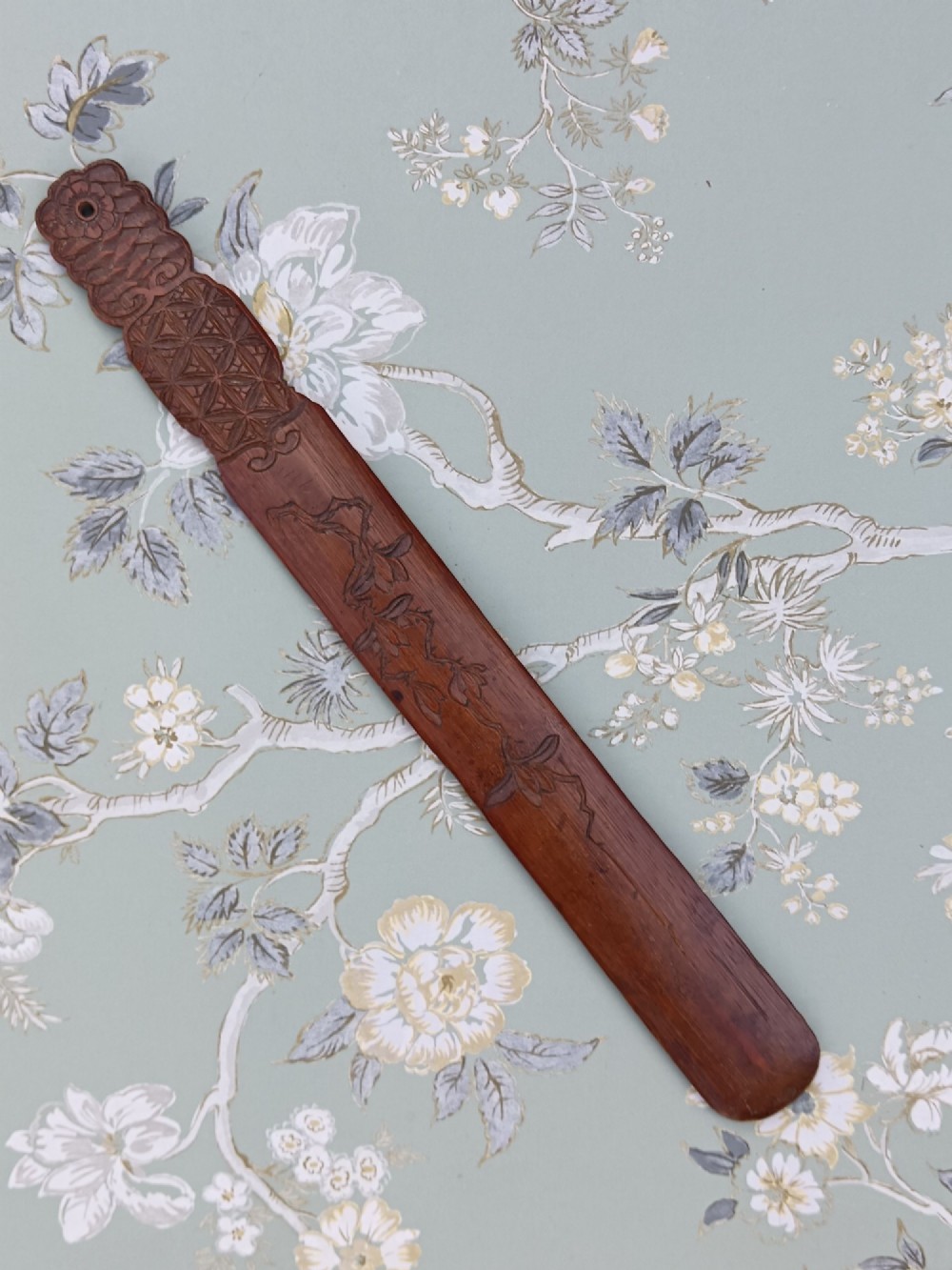 A long, flat carved bamboo page turner featuring relief carvings of a carp, figure, and floral details in a dark reddish-brown finish. View III