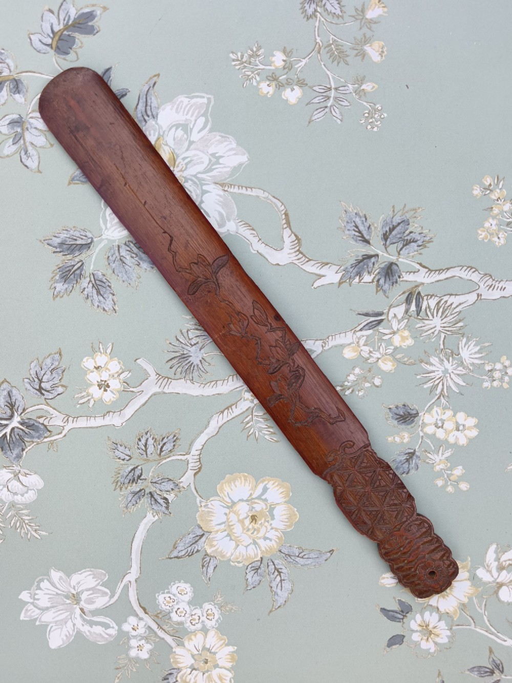 A long, flat carved bamboo page turner featuring relief carvings of a carp, figure, and floral details in a dark reddish-brown finish. View IV