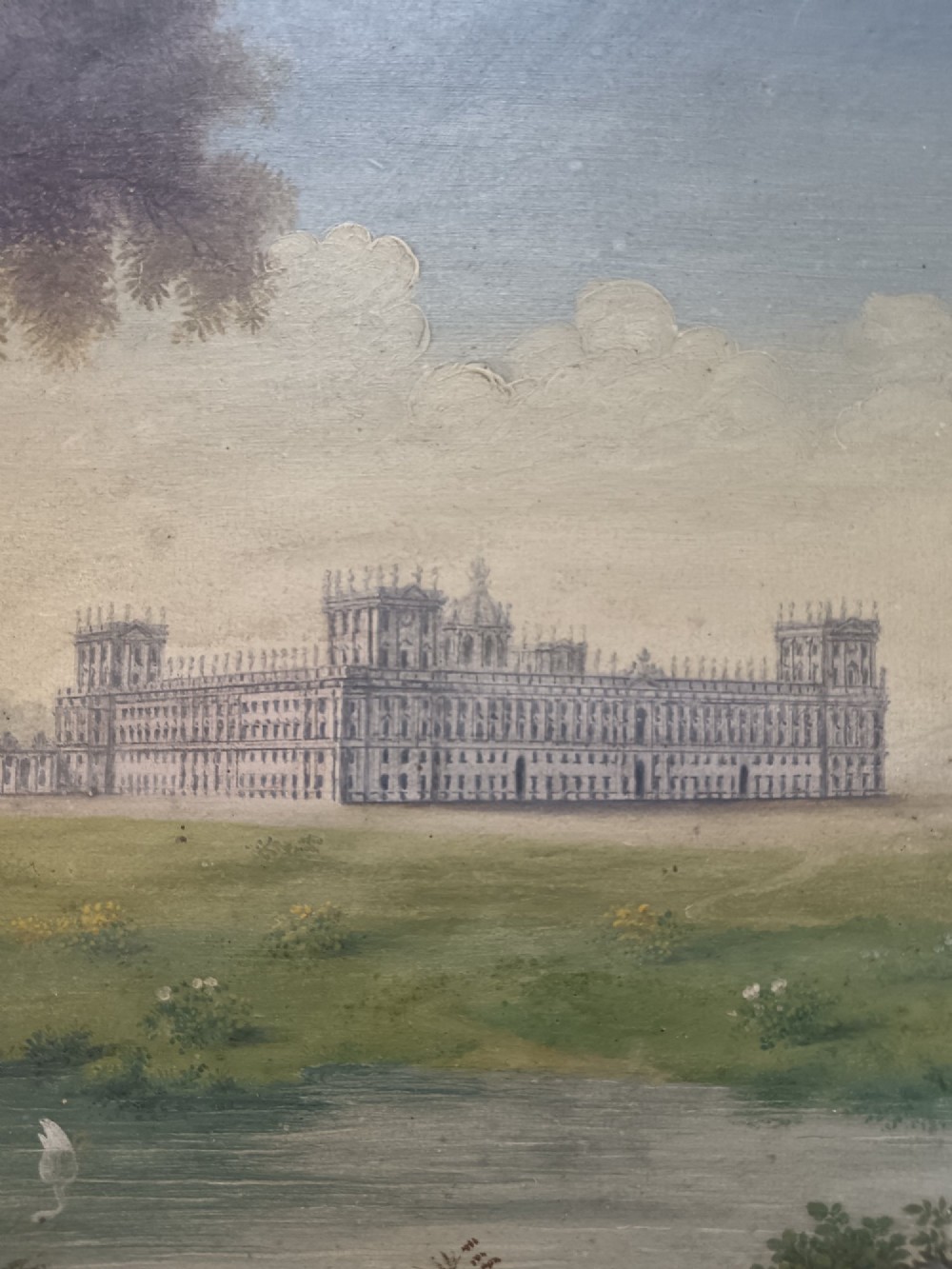 An early nineteenth-century gouache landscape painting depicting a grand palace behind a body of water with swans, presented in a light cream wood frame. View II