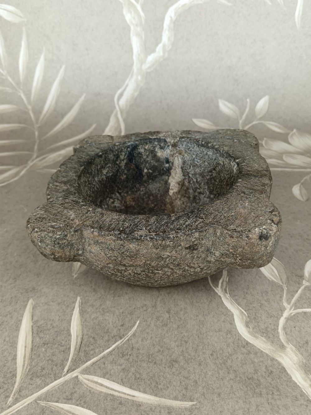 An antique hand-carved stone mortar featuring four corner lugs, shown with a turned fruitwood pestle. View V