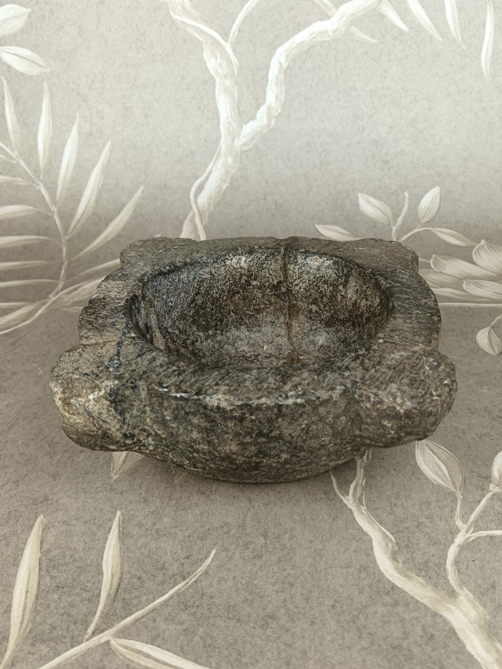 An antique hand-carved stone mortar featuring four corner lugs, shown with a turned fruitwood pestle. View VI