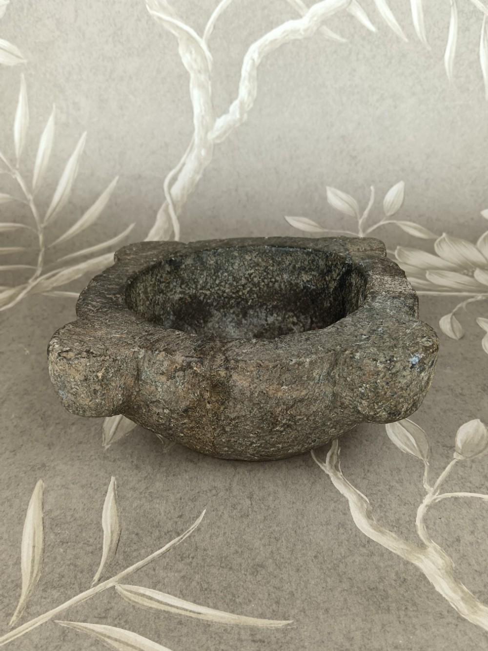 An antique hand-carved stone mortar featuring four corner lugs, shown with a turned fruitwood pestle. View VII