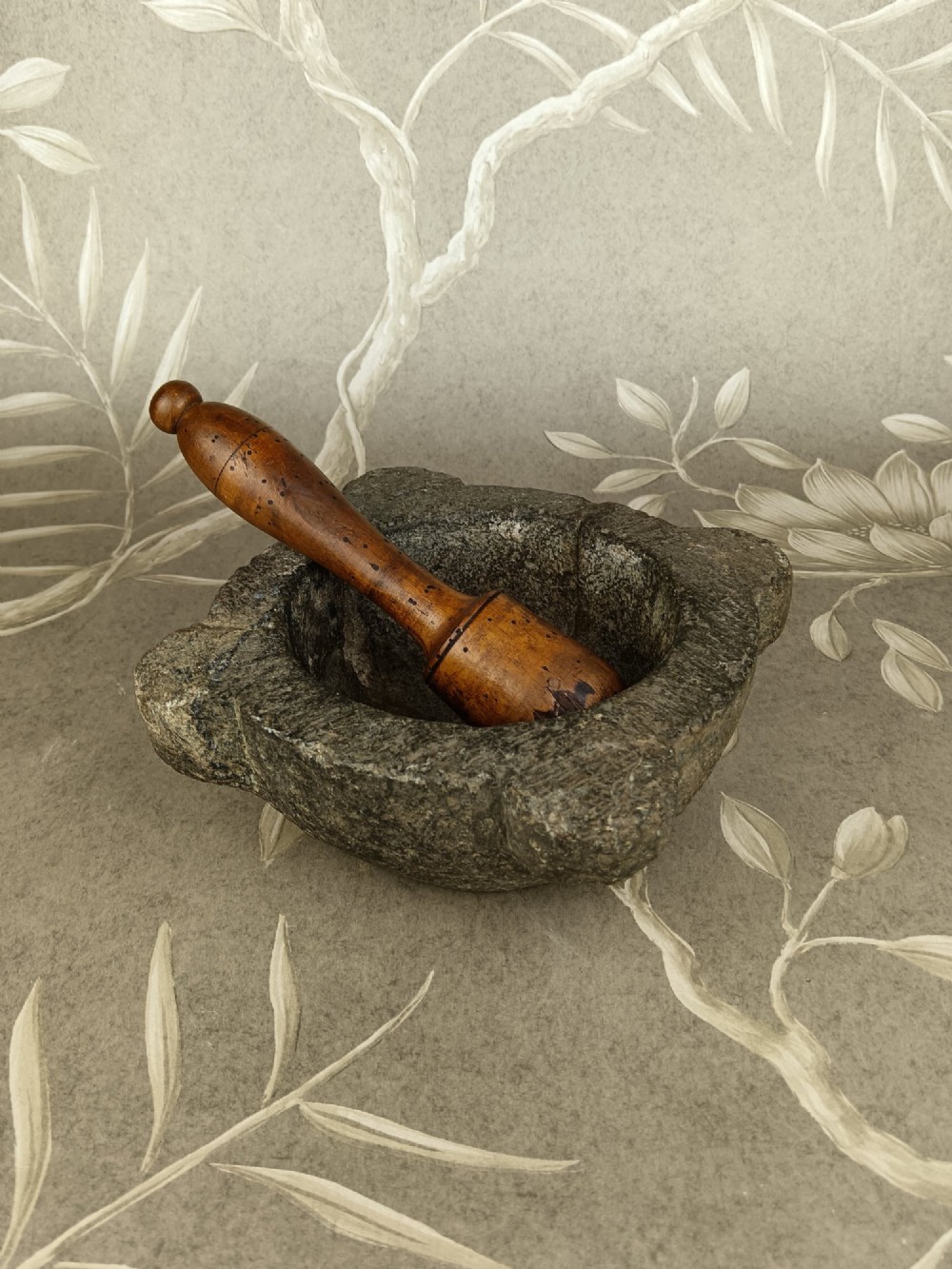 An antique hand-carved stone mortar featuring four corner lugs, shown with a turned fruitwood pestle. View VIII