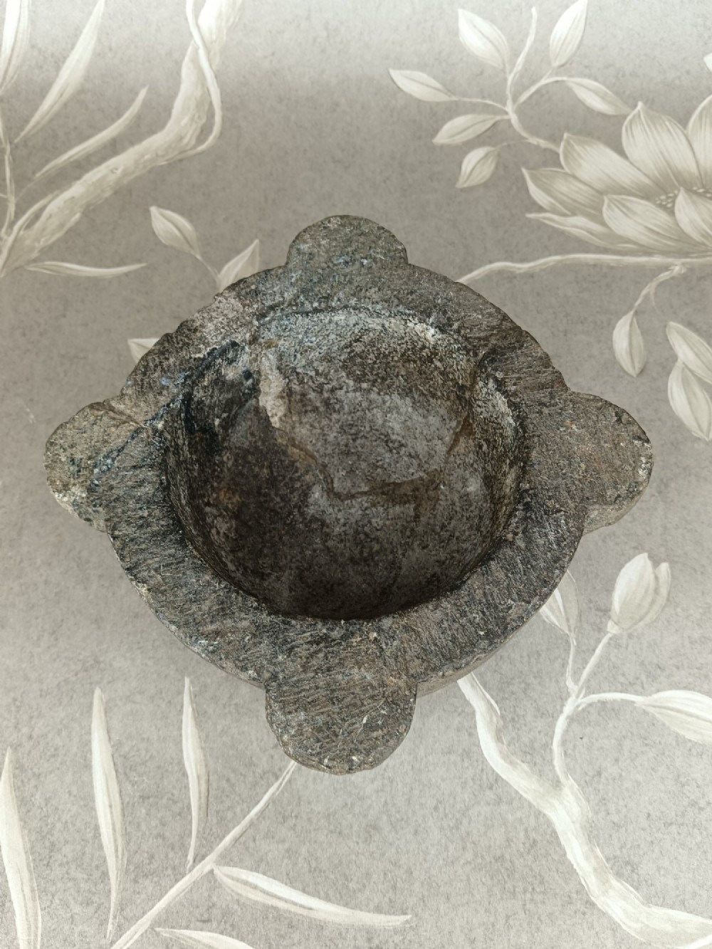 An antique hand-carved stone mortar featuring four corner lugs, shown with a turned fruitwood pestle. View XI