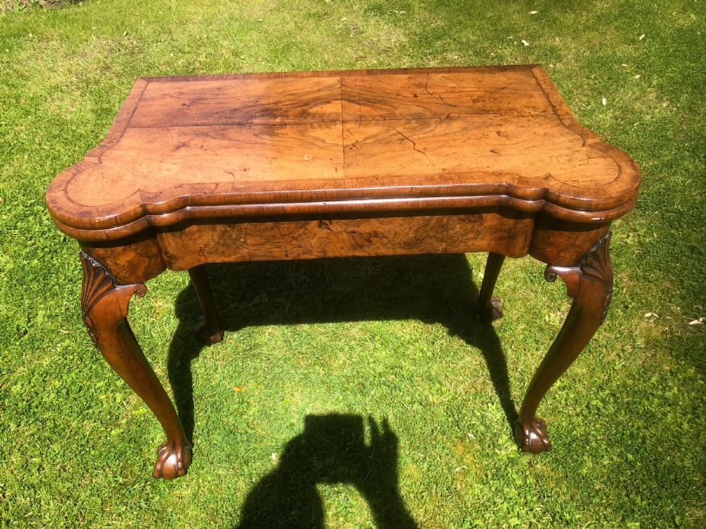 A George II figured walnut folding card table with shaped corners, carved cabriole legs, and ball-and-claw feet. View VI