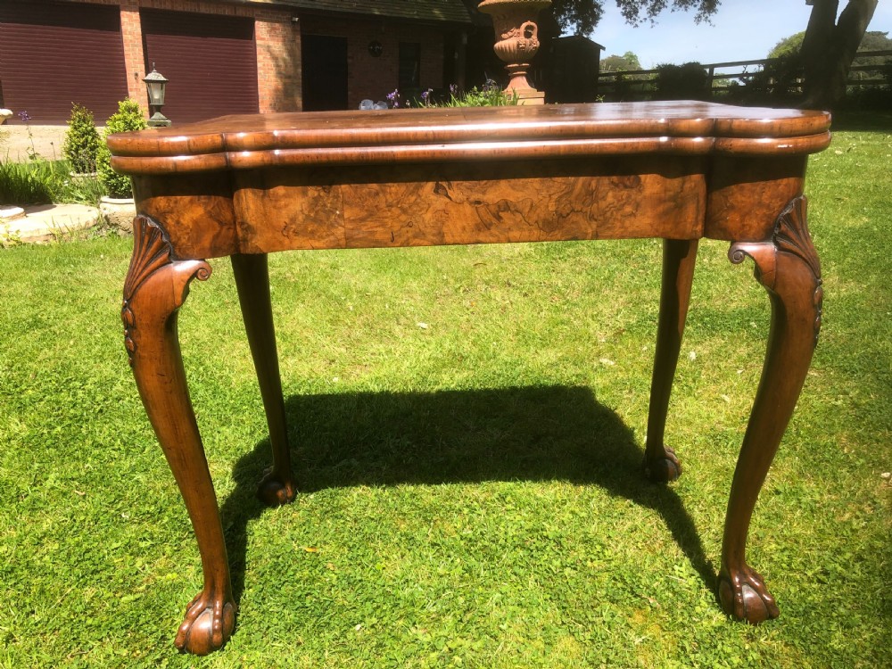 A George II figured walnut folding card table with shaped corners, carved cabriole legs, and ball-and-claw feet. View II