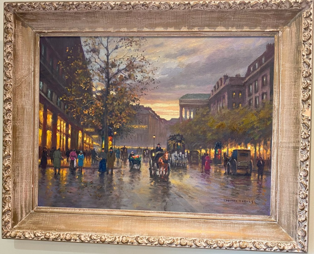 A framed oil painting on canvas depicting a Parisian boulevard at twilight with horse-drawn carriages, figures, and glowing shopfronts.