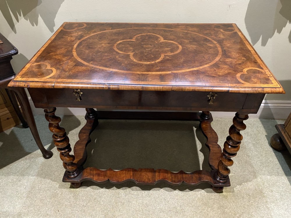 A William and Mary side table featuring an oyster olive veneer top with geometric holly inlays, spiral-turned legs, and shaped stretchers.