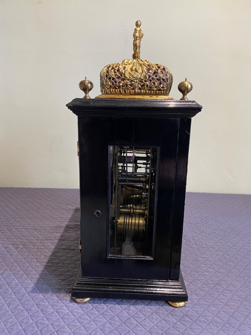 A late seventeenth-century William and Mary ebony table clock featuring an ornate gilded brass basket top with carrying handle and silvered chapter ring. View VIII