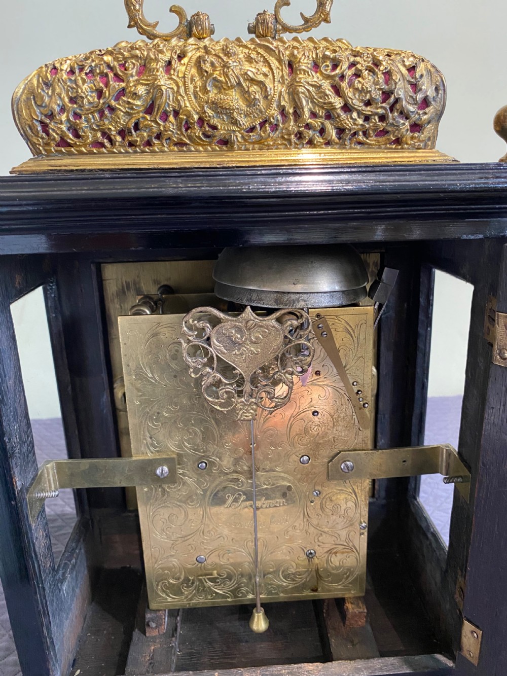 A late seventeenth-century William and Mary ebony table clock featuring an ornate gilded brass basket top with carrying handle and silvered chapter ring. View IV