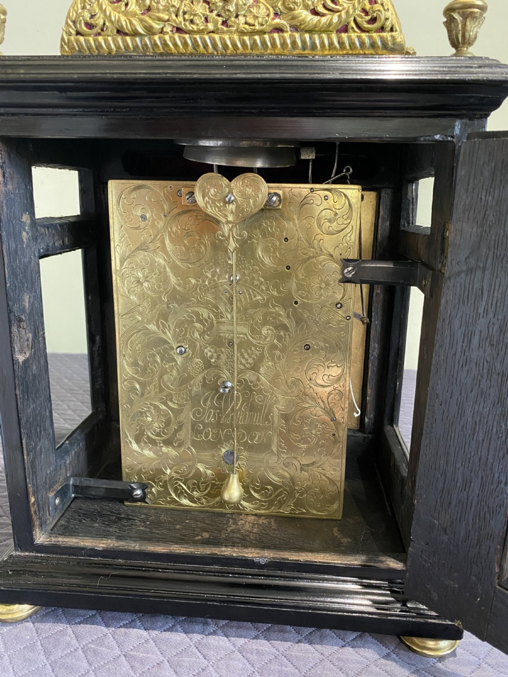 A late 17th-century ebony-veneered table clock with a pierced gilt-brass basket top, decorative finials, and a silvered roman numeral chapter ring. View III