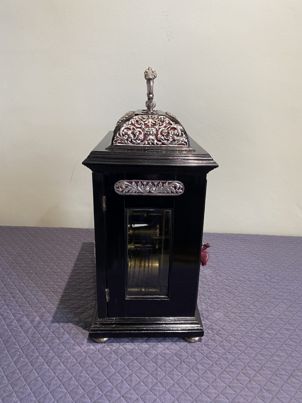 A late 17th-century black ebony table clock featuring repousse silver mounts, an ornate carrying handle, and a brass dial with silvered chapter ring. View III