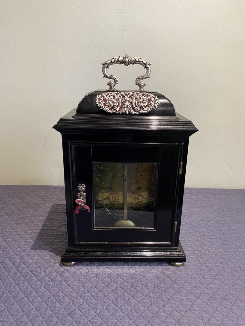 A late 17th-century black ebony table clock featuring repousse silver mounts, an ornate carrying handle, and a brass dial with silvered chapter ring. View IV