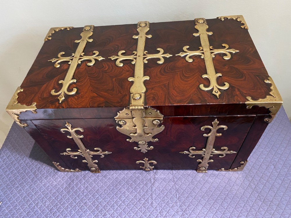 A dark kingwood rectangular cofre forte featuring elaborate brass strapwork, fleur-de-lis mounts, corner brackets, and a matching key in the foreground. View III