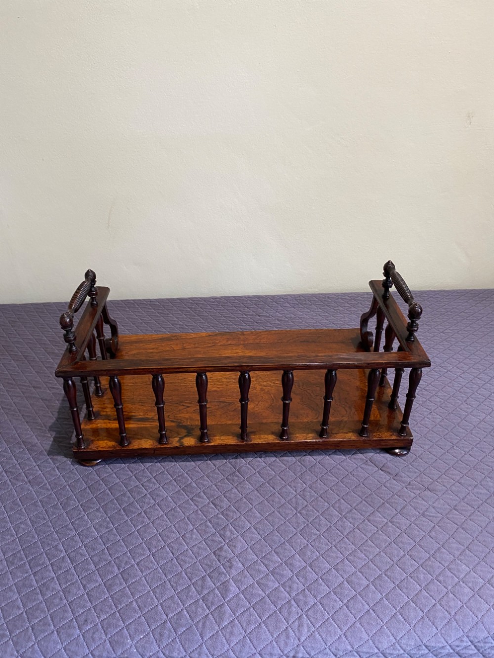 A 19th-century Regency rosewood tabletop book rack featuring a turned spindle back gallery and carved side handles. View II