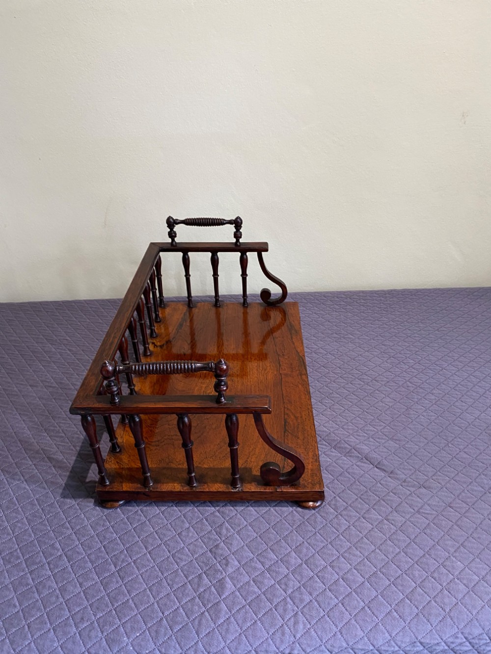 A 19th-century Regency rosewood tabletop book rack featuring a turned spindle back gallery and carved side handles. View IV