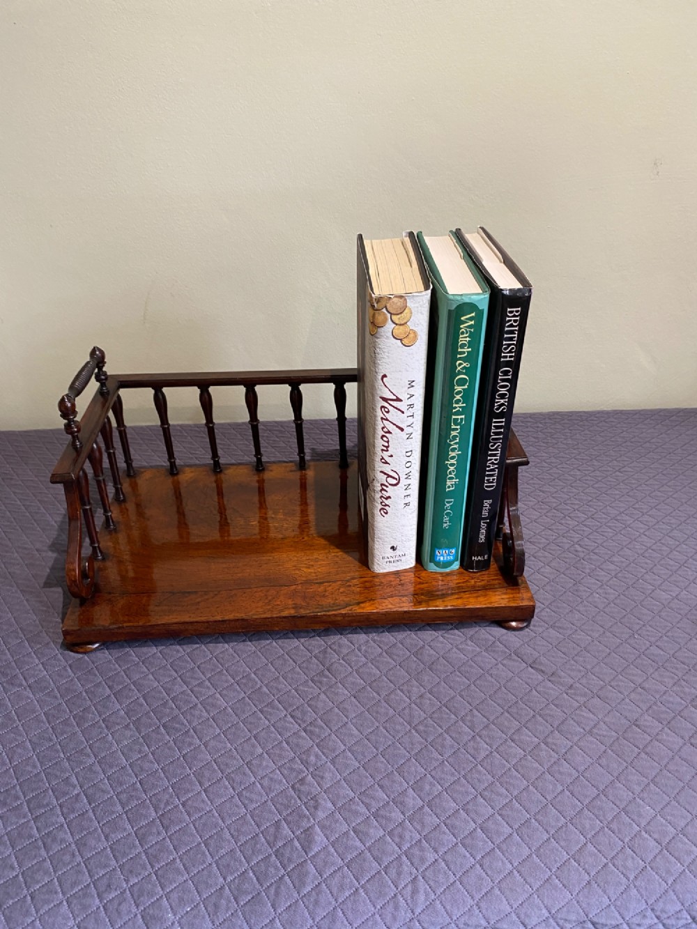 A 19th-century Regency rosewood tabletop book rack featuring a turned spindle back gallery and carved side handles.