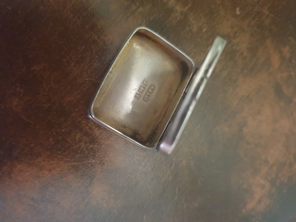 An Edwardian sterling silver rectangular pillbox featuring engraved foliate scrollwork and a central unengraved cartouche. View II