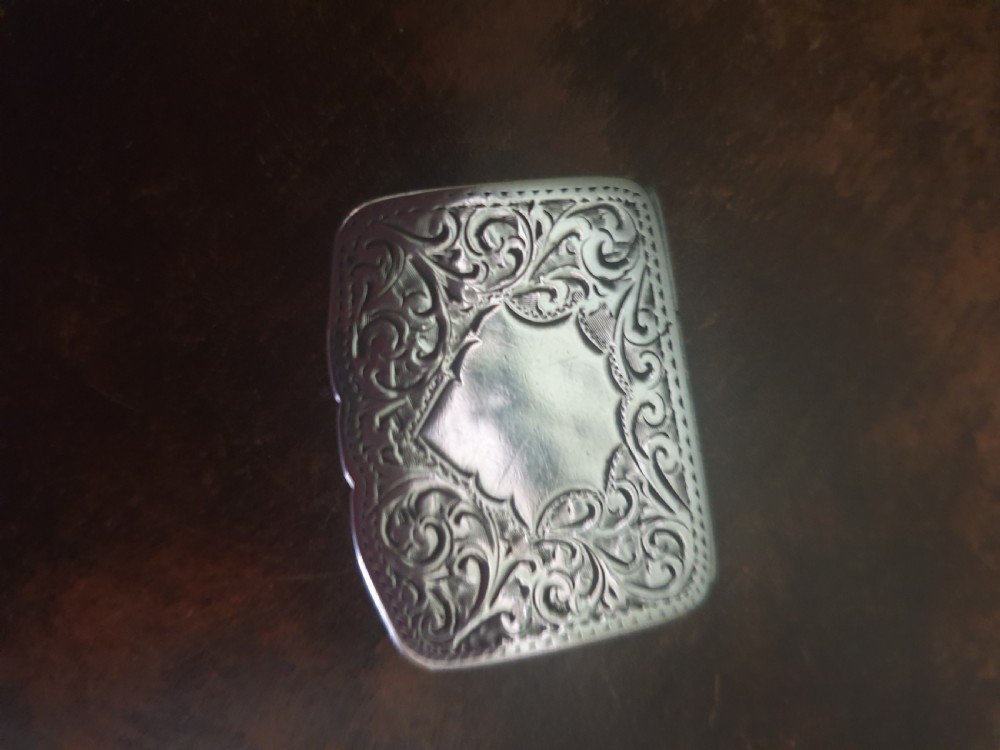 An Edwardian sterling silver rectangular pillbox featuring engraved foliate scrollwork and a central unengraved cartouche. View III