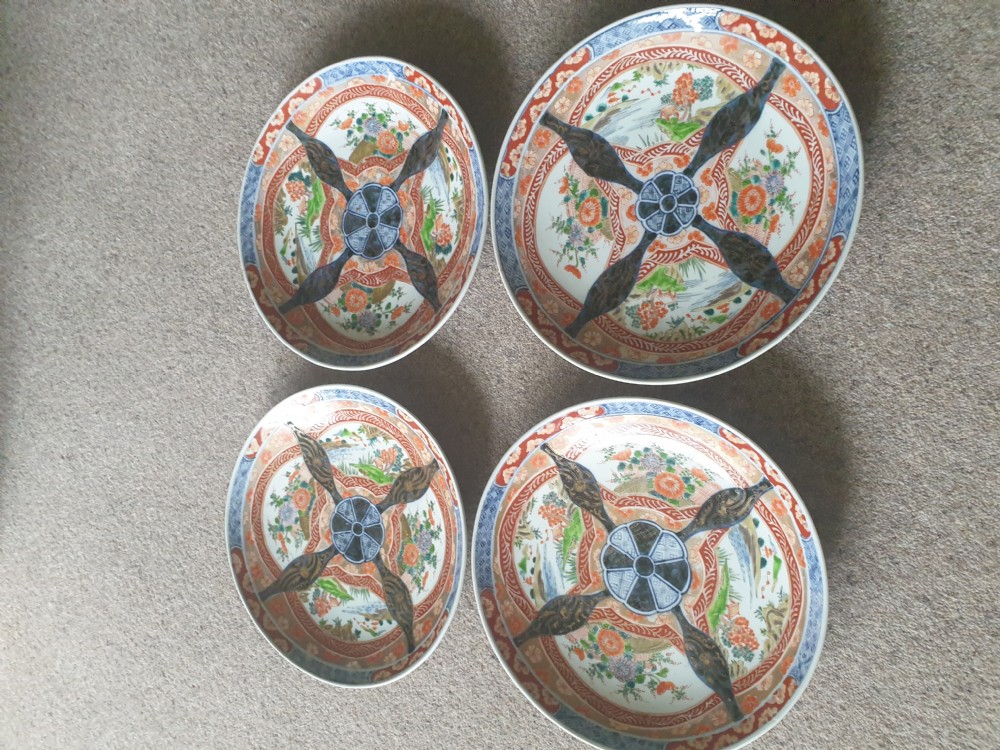A set of four 19th-century Japanese Imari porcelain chargers decorated with intricate iron-red, cobalt blue, and gilded floral motifs.