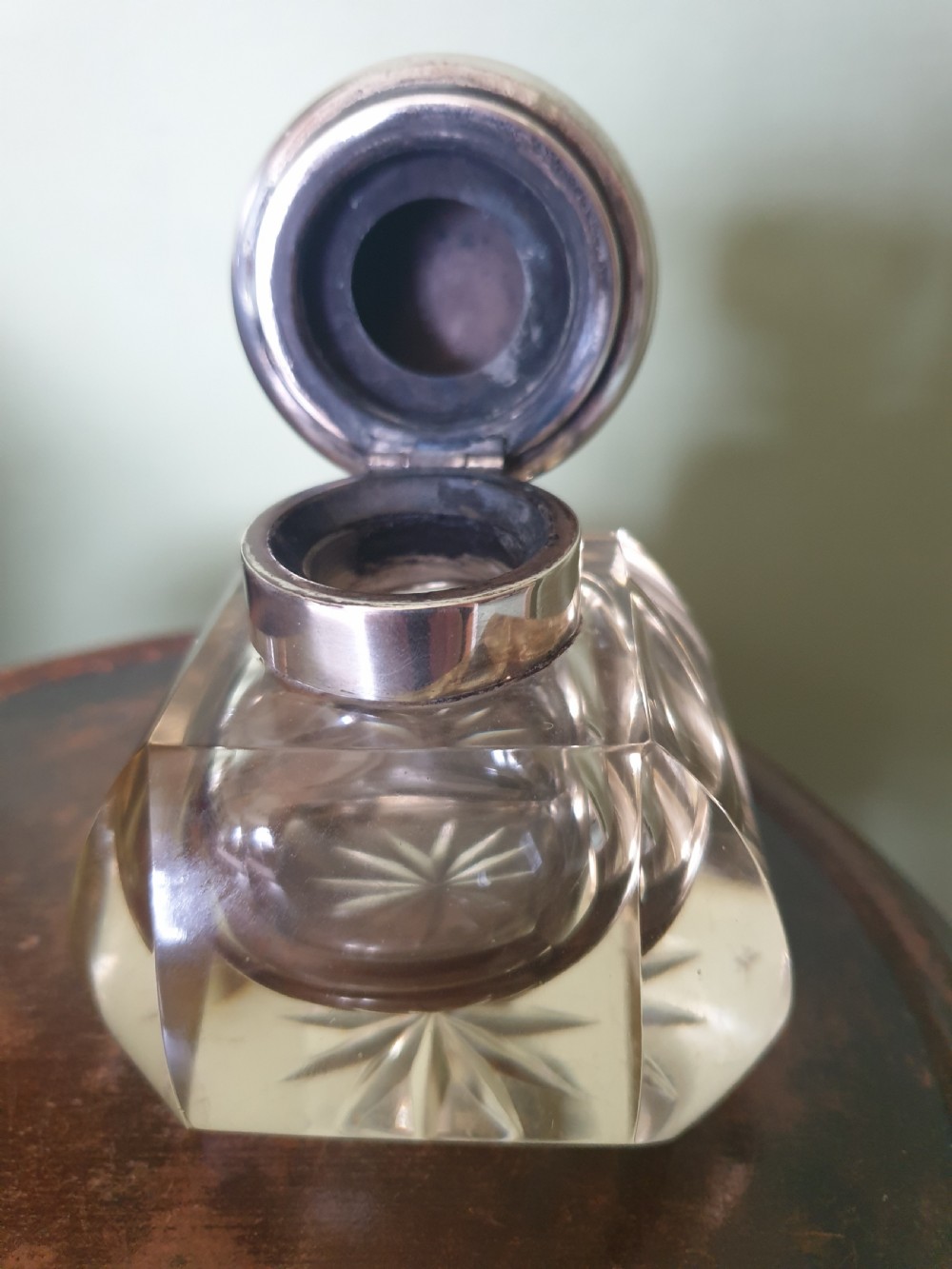 A heavy clear cut-glass inkwell featuring a starburst base design and a polished hinged silver lid with hallmarks. View II