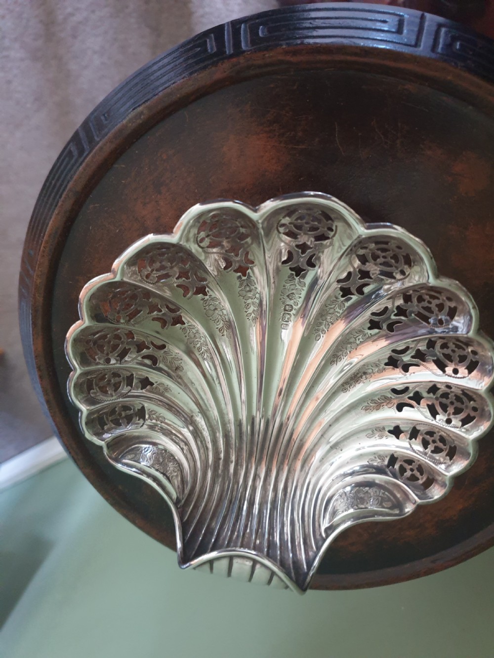 An antique sterling silver dish shaped like a scallop shell featuring intricate pierced lattice work and engraved details, hallmarked in Sheffield 1900.