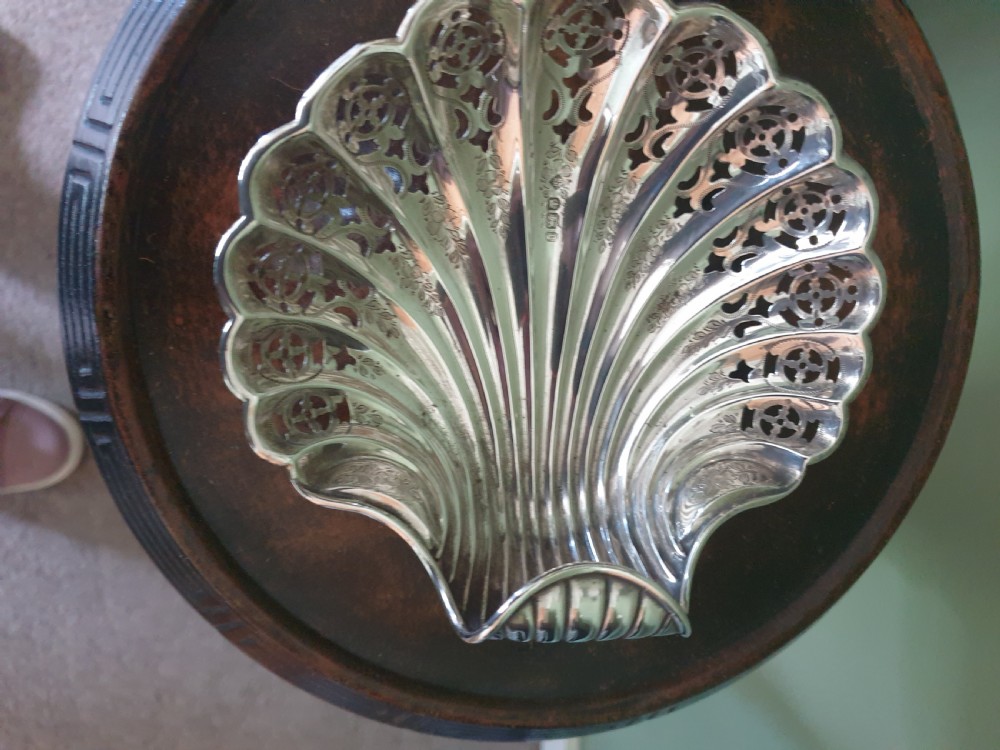 An antique sterling silver dish shaped like a scallop shell featuring intricate pierced lattice work and engraved details, hallmarked in Sheffield 1900. View III