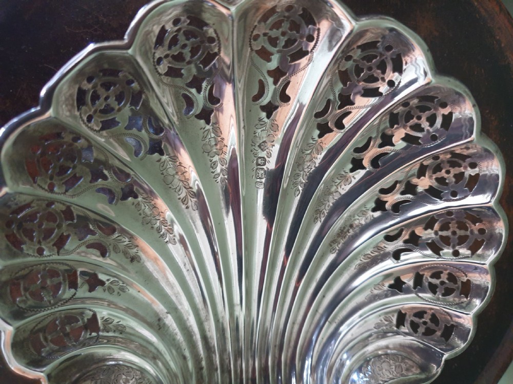 An antique sterling silver dish shaped like a scallop shell featuring intricate pierced lattice work and engraved details, hallmarked in Sheffield 1900. View IV