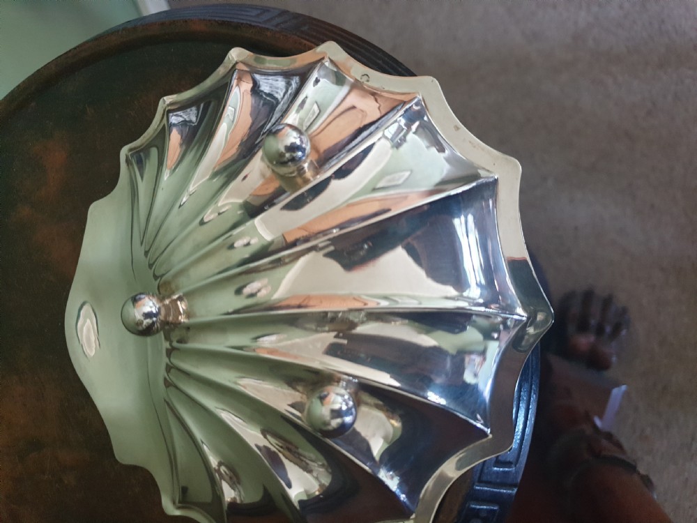 A polished sterling silver dish shaped like a scalloped sea shell with visible British hallmarks on the outer rim. View III
