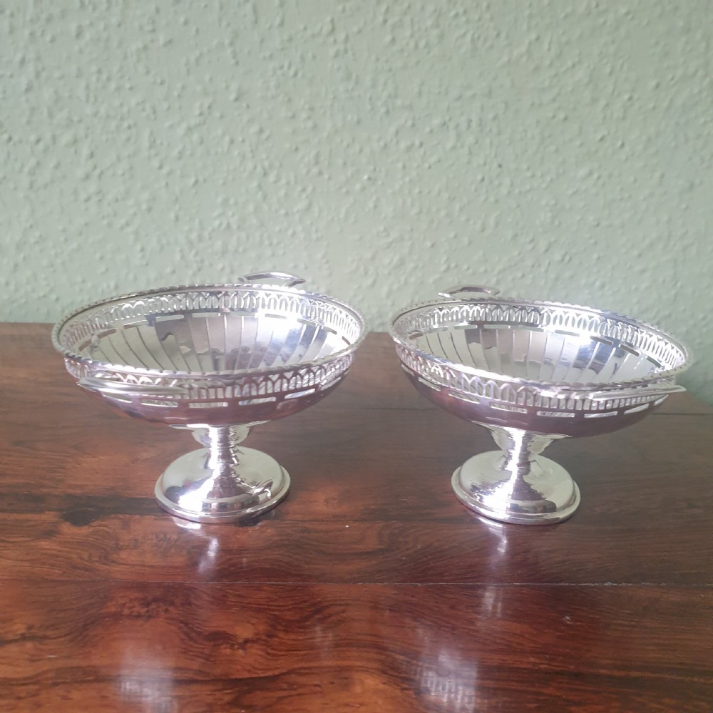 A pair of sterling silver tazzas featuring fluted bowls, pierced geometric rims, twin handles, and circular pedestal feet. View II