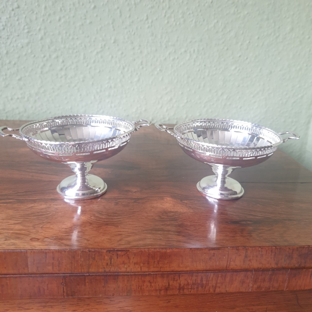 A pair of sterling silver tazzas featuring fluted bowls, pierced geometric rims, twin handles, and circular pedestal feet. View V