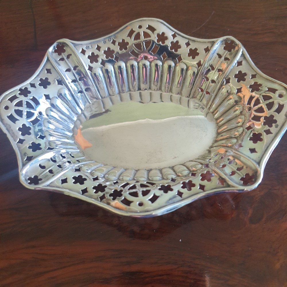 An Edwardian silver dish featuring pierced fretwork motifs along the rim and a fluted central well.