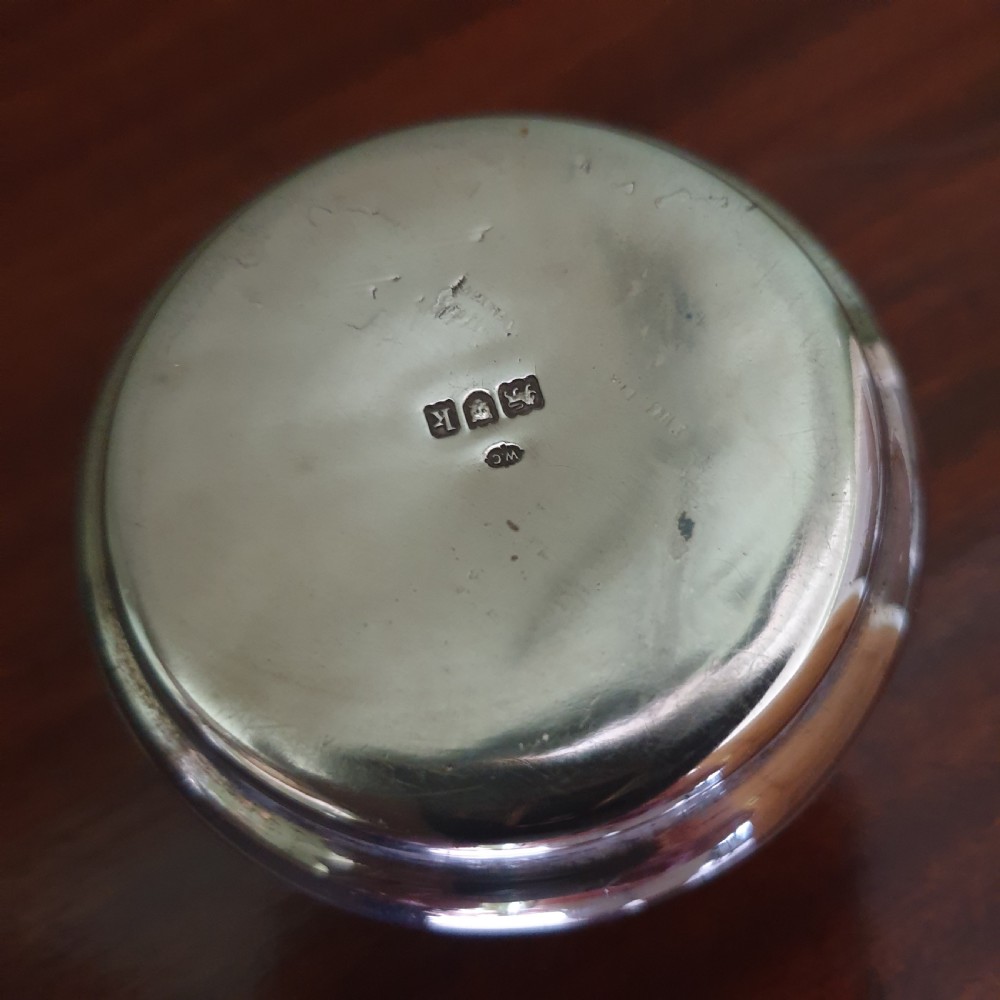 A circular Edwardian sterling silver pot lid featuring embossed figures and official London hallmarks. View V