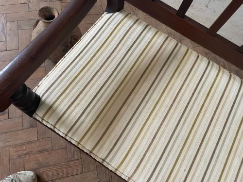 fig 1. A dark wood hallway bench featuring a scalloped top rail, a slatted backrest, turned legs, and a striped fabric seat cushion.