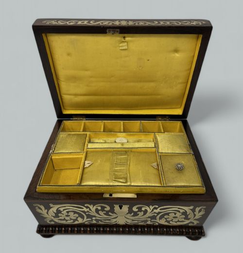 fig 2. An antique dark rosewood rectangular casket featuring detailed brass scrollwork inlay and gadrooned wood edging.