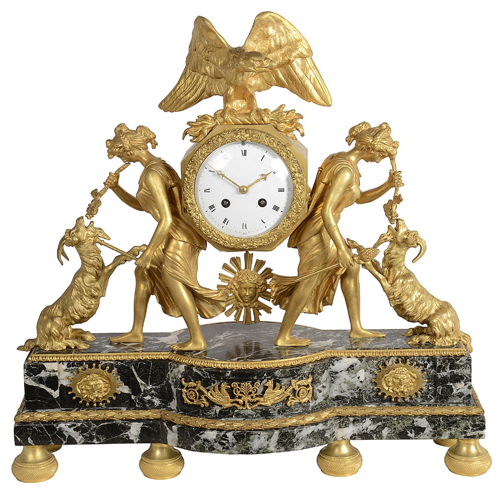 A French Empire gilt bronze and black marble mantel clock featuring an eagle finial, a central circular white clock dial, and classical female figures flanked by goats.