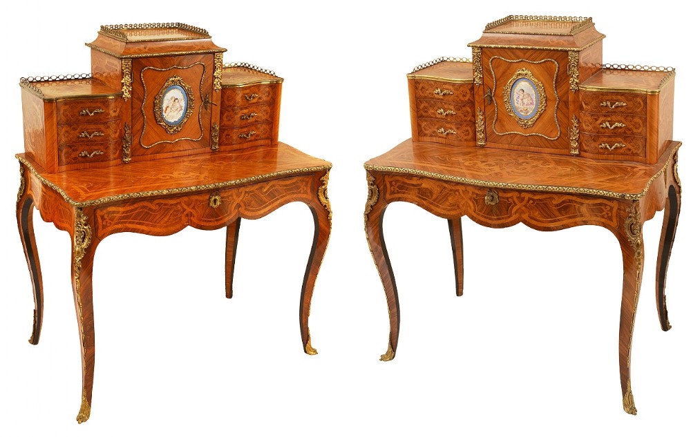 A pair of 19th-century French bonheur du jour desks featuring marquetry veneers, gilt-bronze mounts, central porcelain plaques, and cabriole legs.