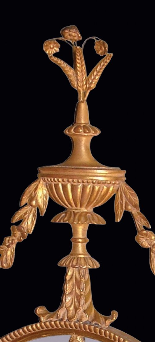 A pair of late 18th-century Neoclassical oval giltwood girandole mirrors with floral swags, urn finials, and twin candle branches. View III