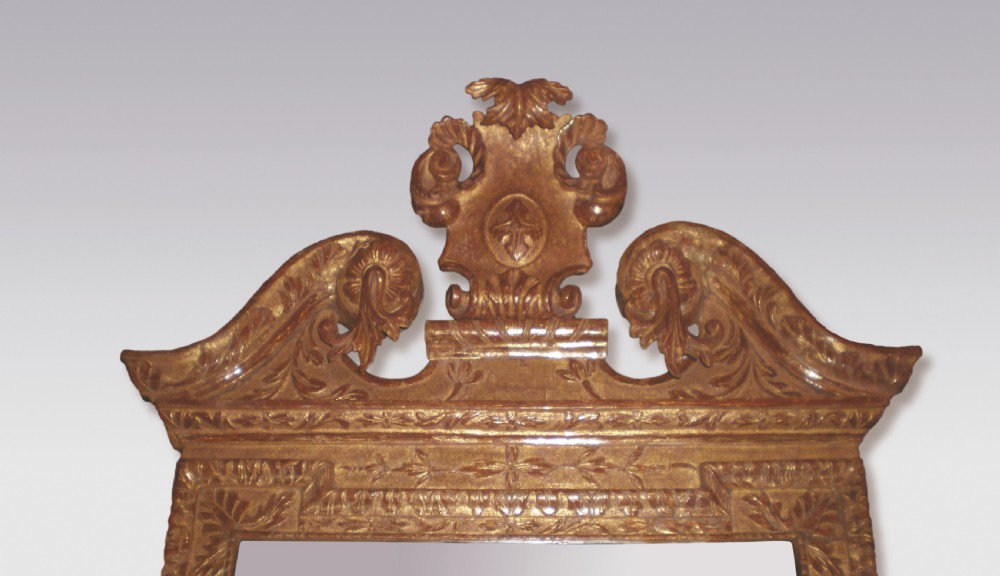 A George II period rectangular gilt gesso wall mirror featuring a broken arch pediment, central cartouche finial, side drapery drops, carved shell apron, and lower brass sconces. View II