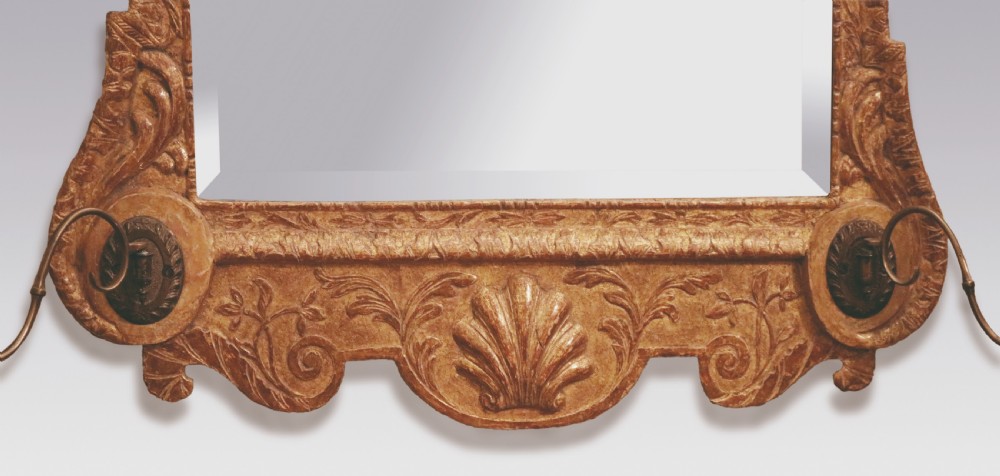 A George II period rectangular gilt gesso wall mirror featuring a broken arch pediment, central cartouche finial, side drapery drops, carved shell apron, and lower brass sconces. View IV