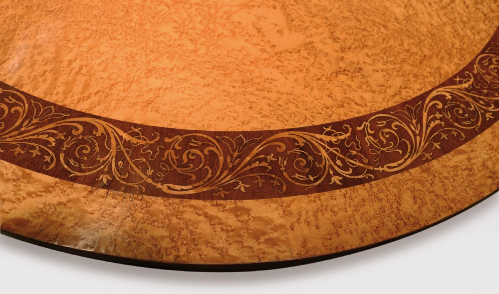 A circular mid-19th-century centre table crafted from birdseye maple featuring an inlaid decorative border, a carved baluster pedestal, and a platform base on carved feet. View III