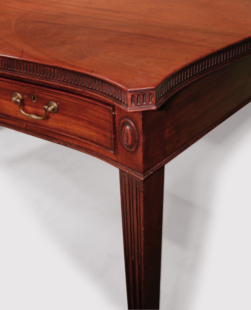 An 18th-century George III mahogany serving table featuring a serpentine front, three drawers with brass swan-neck handles, and fluted square tapered legs. View III