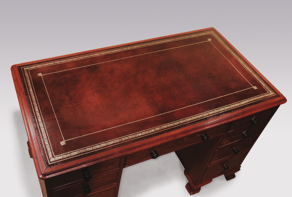 A compact George III mahogany pedestal desk featuring a dark leather writing inset surface, multiple small drawers with turned knobs, and shaped feet. View III